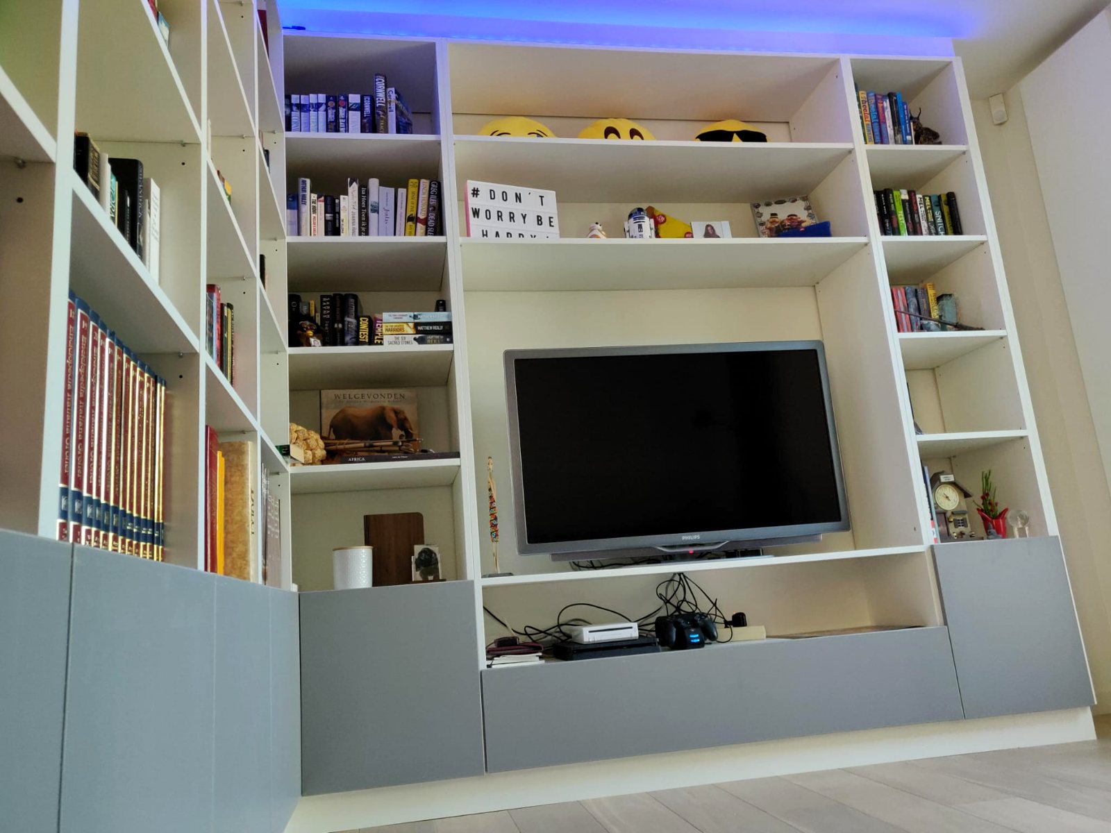 Kamerbrede witte boekenkastenwand met tv-meubel en grijze onderkasten