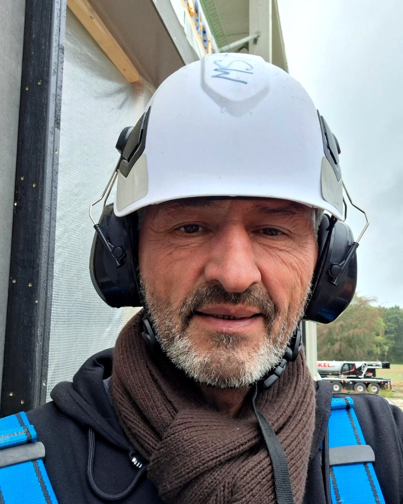 Meté Akinci met bouwhelm en gehoorbescherming op de bouwplaats